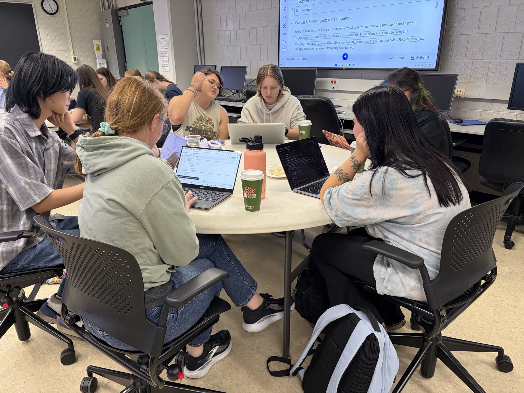 Students collaborate around a table with laptops during the capstone