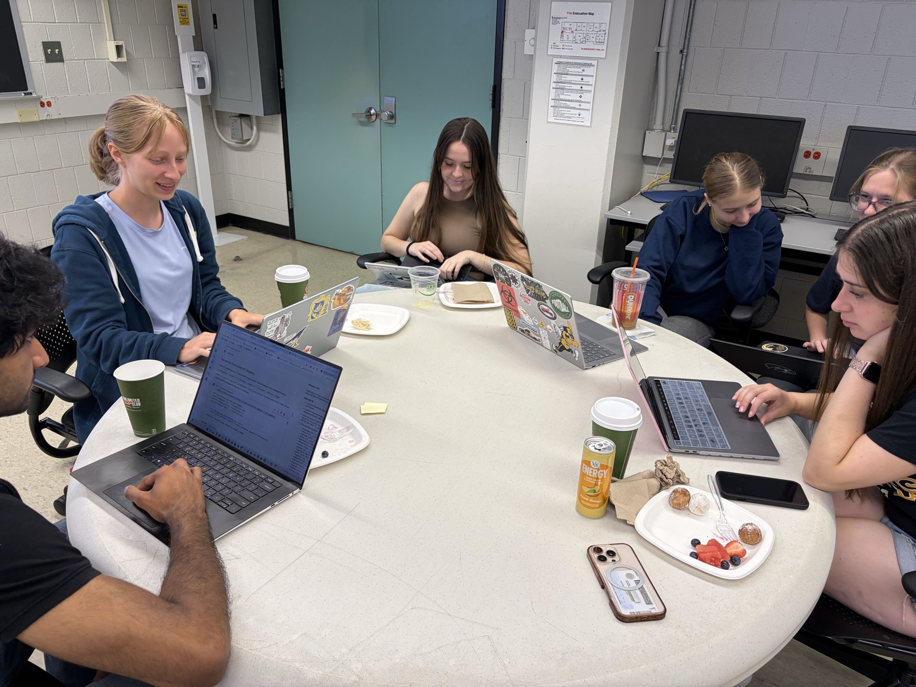 A second team of students discusses code around a table